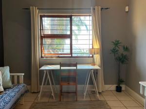 a table and chairs in a room with a window at The Sync Inn in Gqeberha
