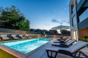 a swimming pool with lounge chairs and an umbrella at Sunny Oasis in Bibinje