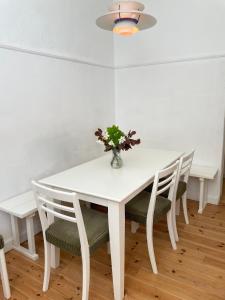 a white dining room table with chairs and a vase with flowers at Lundsgaard Gods ferielejlighed in Kerteminde