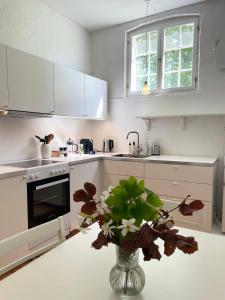 a white kitchen with a vase of flowers on a table at Lundsgaard Gods ferielejlighed in Kerteminde