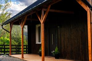 a cabin with a wooden porch and a black door at Casa de Lângă Mesteceni in Dealu Negru