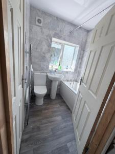 a bathroom with a toilet and a sink and a window at Nuneaton 3 Bedroom House with Drive and Garden Sleeps 5 in Attleborough
