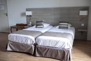 two beds in a hotel room with two pillows at Hôtel de la Poste Restaurant Benjamin Linard in Pouilly-en-Auxois