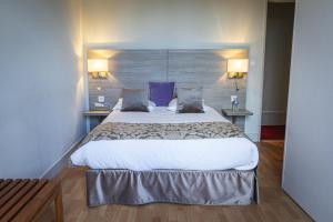 a large bed in a hotel room with two lamps at Hôtel de la Poste Restaurant Benjamin Linard in Pouilly-en-Auxois