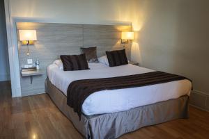 a large bed in a hotel room with two lamps at Hôtel de la Poste Restaurant Benjamin Linard in Pouilly-en-Auxois +4 photos