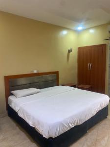 a bedroom with a large bed and a wooden cabinet at Hymax Grace hotel in Bolorunpelu +5 photos