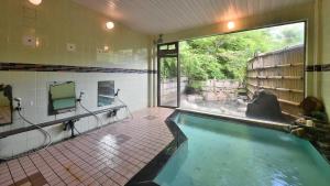 a swimming pool in a bathroom with a large window at Masuya Ryokan in Aoki