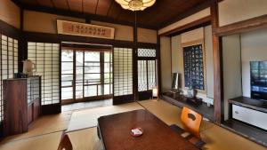 a living room with a table and chairs and windows at Masuya Ryokan in Aoki