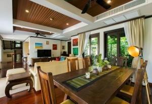 a dining room and living room with a wooden table at Katamanda Villa Chanti Pool Villa Kata in Kata Beach