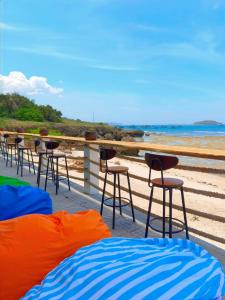 a row of bar stools on a balcony overlooking the beach at Hon Do Eco Retreat in Mỹ Thanh