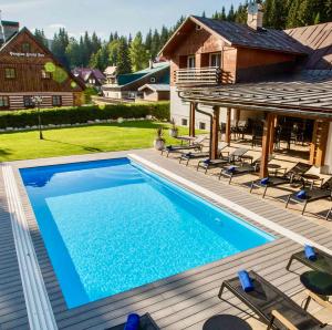 a swimming pool with chairs and a house at Chalet Schäfer s vyhřívaným bazénem se slanou vodou a saunou in Harrachov