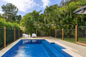 a swimming pool with two chairs and a fence at Blue Gum Hideaway Pet friendly Fire Pit in Coolum Beach