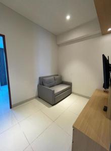 a room with a chair and a television in it at Apartemen Roseville at BSD by Kenkei in Dadap