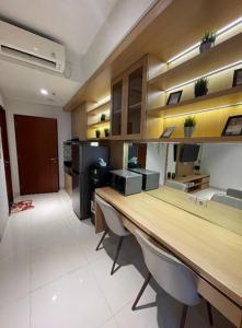 a kitchen with a long desk with chairs in a room at Apartemen Roseville at BSD by Kenkei in Dadap