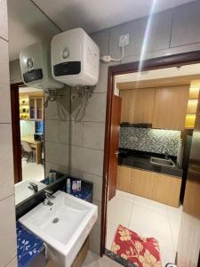 a small bathroom with a sink and a kitchen at Apartemen Roseville at BSD by Kenkei in Dadap