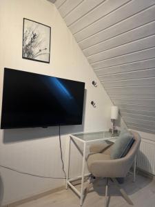 a tv on a wall with a chair and a desk at Villa Malena Guesthouse in Fensmark