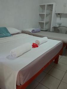 two beds with white towels and a red rose on them at Kathy B Guesthouse in Luganville