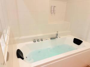 a white bath tub with a blue water in it at Jacuzzi privé - Netflix - Wi-Fi - parking gratuit in Châtel-Guyon