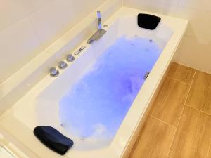 a bath tub filled with blue water with a knife at Jacuzzi privé - Netflix - Wi-Fi - parking gratuit in Châtel-Guyon +18 photos