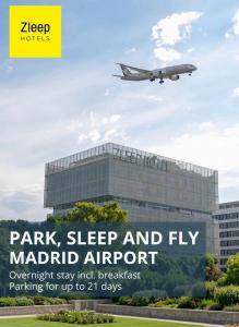 an airplane is flying over a building with a sign at Zleep Madrid Airport in Madrid