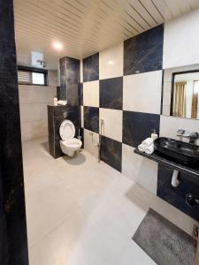 a bathroom with a toilet and a sink at Hotel Vivanta in Bānswāra +2 photos
