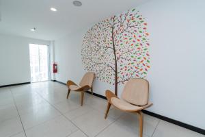 a waiting room with three chairs and a tree on the wall at Kingston Hotel 22 - Cheras, Kuala Lumpur in Kuala Lumpur