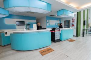 two people in a kitchen with blue cabinets at Kingston Hotel 22 - Cheras, Kuala Lumpur in Kuala Lumpur