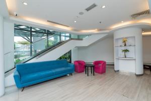 a living room with a blue couch and pink chairs at Kingston Hotel 22 - Cheras, Kuala Lumpur in Kuala Lumpur