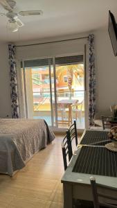 a bedroom with a bed and a table and a patio at Roquetas "Estudio acogedor cerca del Castillo y del puerto de Roquetas, aireconditionado" in Roquetas de Mar