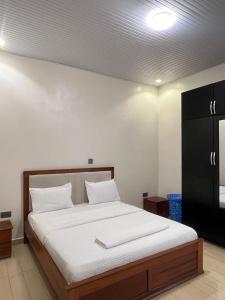 a bedroom with a large bed with white sheets at KIGALI E6 APARTMENTs RESORTS in Kigali