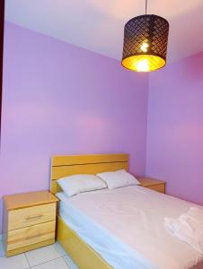 a bedroom with purple walls and a bed and a lamp at Comfort Apartment in Einzorene
