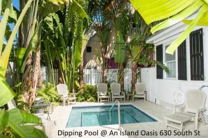a swimming pool in front of a house with palm trees at An Island Oasis in Key West
