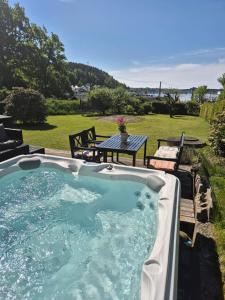 a hot tub in a backyard with a table and bench at Solheimhuset - feriehus nær Tjøme og VerdensEnde in Tokenes +12 photos