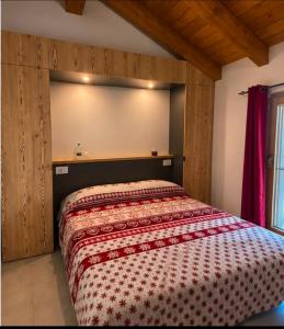 a bedroom with a bed with a red and white comforter at Mondo D'Oro in Macugnaga