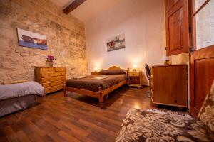a bedroom with two beds and a stone wall at 3Cities Maison close to Valletta in Cospicua