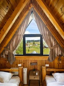 two beds in a room with a large window at Mountain Whisper in Žabljak