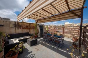 a patio with a table and chairs on a roof at 3Cities Maison close to Valletta in Cospicua