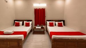 two beds in a room with red curtains at MKR GRANd in Rāmeswaram