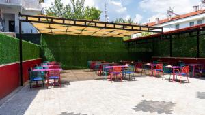 a patio with colorful tables and chairs under a wooden canopy at Ermet Homes Apart in Koycegiz