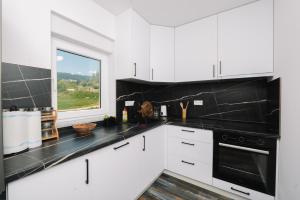 a kitchen with white cabinets and a window at Vila Paola in Kupres