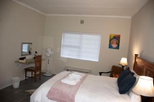 a bedroom with a bed and a desk and a window at Tooiselvere in George