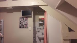 a bathroom with a sink and a tv on the wall at Le Relais De Risquetout in Hem-Hardinval