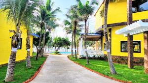 a yellow building with palm trees next to a sidewalk at Sun resort & villa beach in Tiến Thành