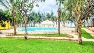 a pool with an umbrella in a park with palm trees at Sun resort & villa beach in Tiến Thành