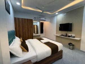 a bedroom with a large bed and a flat screen tv at Hotel V Stay in Chennai