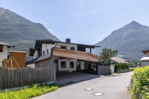 a house with a fence and mountains in the background at LIDA CHALET in Längenfeld