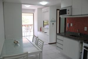 eine Küche mit einem Glastisch und einer Arbeitsplatte in der Unterkunft Nannai Residence - Muro Alto in Porto De Galinhas