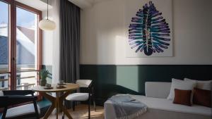 ein Wohnzimmer mit einem Bett, einem Tisch und einem Fenster in der Unterkunft Almanac X Alcron Prague in Prag