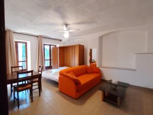 a living room with an orange couch and a bed at Will House 1 in Lanzo Torinese