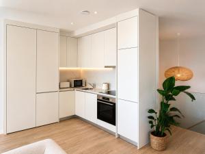 a kitchen with white cabinets and a potted plant at Terra Clara Studios & Apartments in Esposende